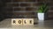 Role word from wooden blocks on desk