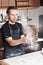 Roll out the dough. expanding cloud of flour. Closeup hand of chef baker in uniform blue apron cook pizza at kitchen