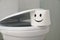 Roll of paper with drawn funny face on toilet in bathroom, closeup