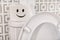 Roll of paper with funny face on toilet tank in bathroom