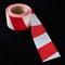 Roll of red and white caution tape against a dark background