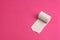 Roll of rough white toilet paper on pink background, close-up, copy space, concept of stomach problems or diarrhea