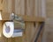 A roll of toilet paper on a modern holder, in a rustic, wooden restroom WC. Horizontal photo