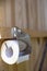 A roll of toilet paper on a modern holder, in a rustic, wooden restroom WC. Vertical photo