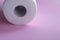 Roll of white disposable nonwoven fabric napkins isolated on pink