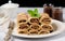 Rolled crepes or tiny pancakes with rich chocolate, displayed on a crisp white plate