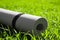Rolled karemat or fitness mat on green grass outdoors, closeup