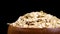 Rolled oats in wooden bowl. Dry whole grain oatmeal on black background.