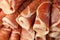 Rolled slices of delicious jamon as background, closeup
