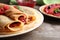 Rolled thin pancakes with sweet jam and berries on plate, closeup