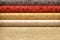 Rolled up rolls of vinyl wallpaper. Different textures and colors, as background. Red, yellow, beige wallpaper with