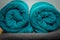 Rolled up turquoise towels located on a gray towel