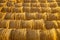 Rollers made of dry pressed yellow straw, stacked in a pyramid in a field, against a blue sky