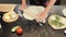Rolling dough with rolling pin. Female hands roll raw dough for pizza. Preparing original italian pizza. Cooking process. Baking c