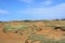 Rolling rust colored dirt hills with sparse plants and grasses in Hawaii