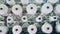 Rolling sewing spools with warping white threads. Textile factory equipment.