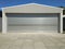 Rolling shutter door of large garage warehouse entrance with concrete blocked floor, industry building background with blue sky.