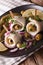 rollmops herring with olives, onions, pickles and lemon close-up. Vertical