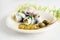 Rollmops or rolled pickled herring with red onions, gherkins and capers on a white table with party streamer, a traditional sour