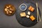 Rolls mini set on a round board next to sticks, soy sauce and baked champignons on a black background.