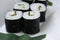 Rolls of sushi with rice nori seeweed and fish on a white plate with hashi chopsticks