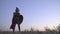 Roman legionary in an armor helmet with a sword and shield stands in the field before dawn