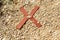 The Roman numeral ten is laid out in red brick on gravel. The cross is depicted with bricks on pebbles