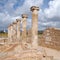 Roman walls and columns in the house of theseus in paphos cyprus with the historic lighthouse in the distance