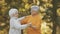 Romance at old age. Elderly retired couple dancing in the park in autumn