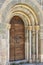 Romanesque entrance arch and capital with antique wooden door