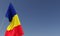 Romania flag on flagpole on blue background. Place for text. The flag is unfurling in wind. Europe, Bucharest. Romanian. 3D