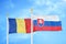 Romania and Slovakia two flags on flagpoles and blue sky