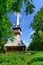 Romanian wooden church with far airplane in the sky.