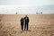 Romantic aged couple walking on beach at midday. Man hugs woman. Man and woman in love