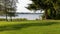 Romantic bathing place on the lake with stairs into the water, bathing hut, lawn and large spruce