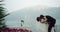 Romantic and beautiful couple groom and bride in amazing place beside of flowers field background mountain and lake they