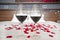 Romantic bedroom - glasses of red wine and rose petals on a bed