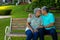 Romantic biracial senior husband kissing senior woman while sitting on bench in park