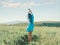 Romantic blue hair woman standing with hands up in summer meadow.