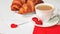 A romantic breakfast for a loved one on Valentine`s Day. Fresh delicious croissants with a cup of coffee, love letter, present on