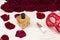Romantic carnival concept. Red carnival mask, bouquet of red roses, lipstick and bottle of perfume on light wooden background
