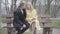 Romantic Caucasian couple sitting on bench in park, talking and rubbing noses. Portrait of loving adult man and woman