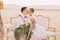 The romantic close-up portrait of the groom kissing the bride with the bouquet into the cheek in the sunny field. The