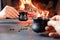 Romantic coffee break. A couple drinks coffee from ceramic coffee cups against a backdrop of burning fire and coffee beans. Close-