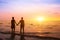Romantic couple on the beach at sunset watching horizon, honeymoon vacation holidays at sea destination, silhouette of two lovers