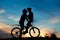 Romantic couple of cyclists is kissing at sunset.