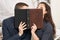 Romantic couple drinking tea with cookies, kissing behind photo album