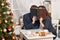 Romantic couple drinking tea with cookies, kissing behind photo album