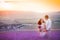 Romantic couple in an endless lavender field at sunset. blond Man and red-haired girl with a bouquet of flowers in love