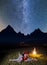 Romantic couple - girl and guy lying near the fire, enjoying incredibly beautiful starry sky. Long exposure